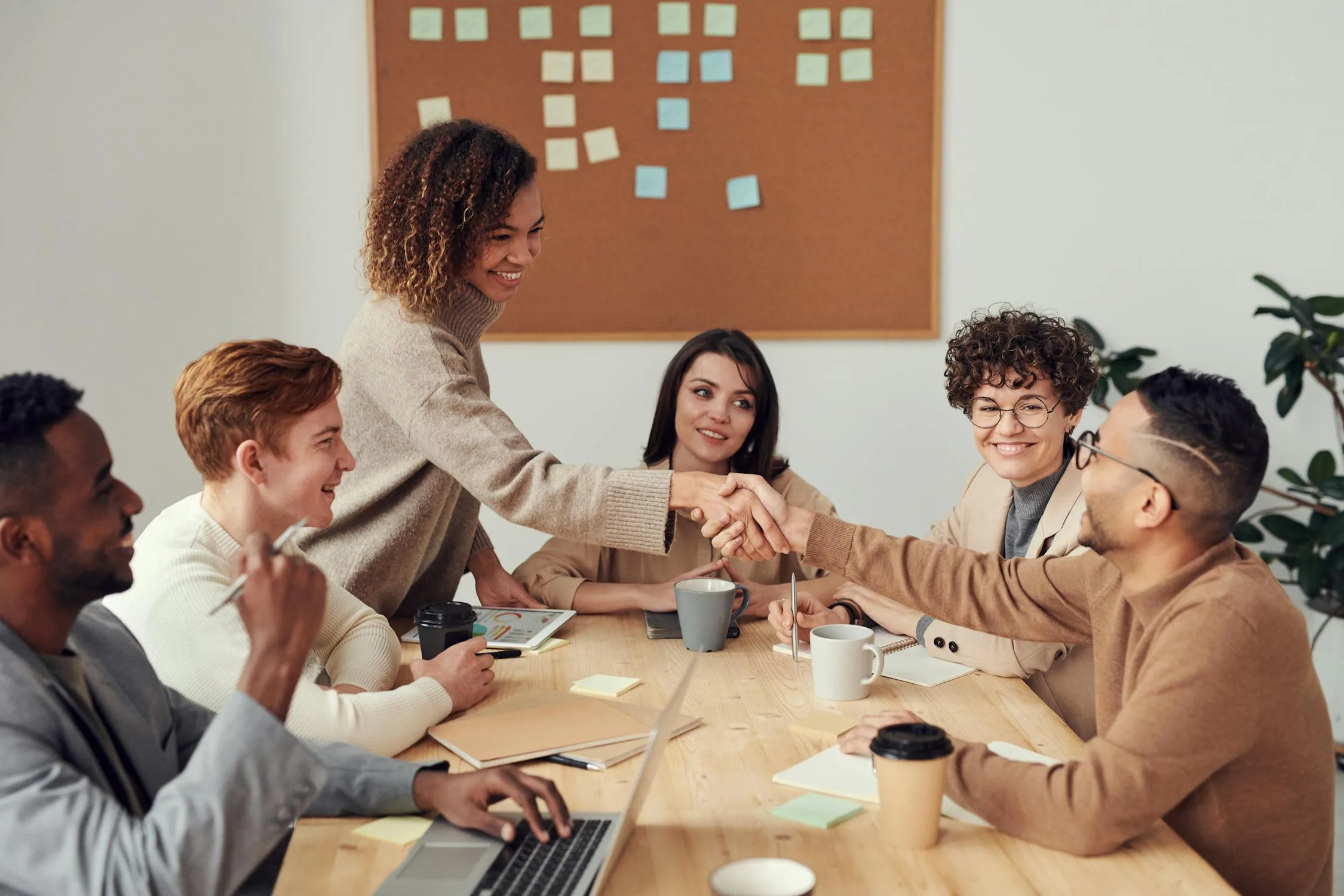 Diverse team collaborating around conference table with laptops
