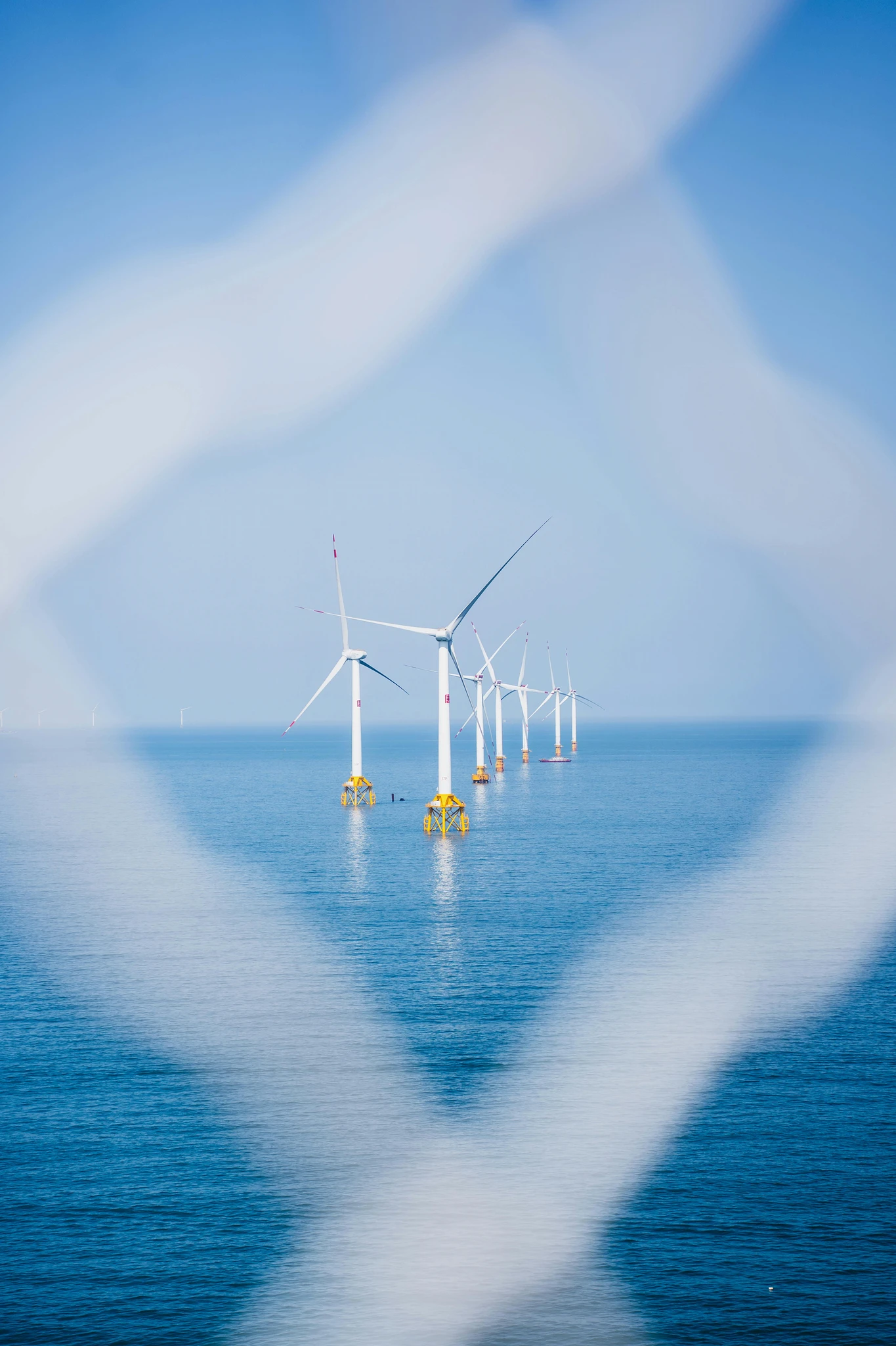 Offshore wind turbines seen through a wire fence