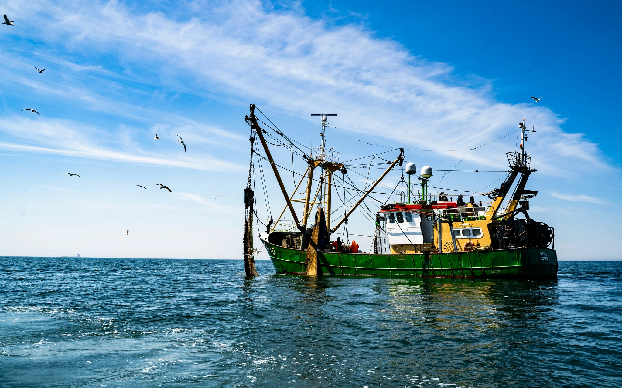 A fishing trawler at sea with gulls overhead