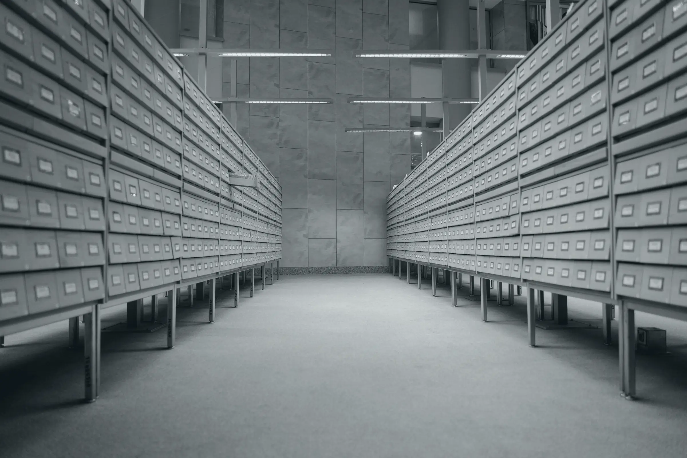 A long archive room lined with shelves of drawers