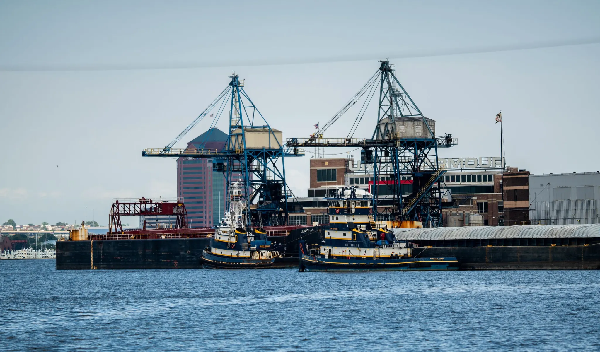 Cranes, tugboats, and a barge in Baltimore Harbor